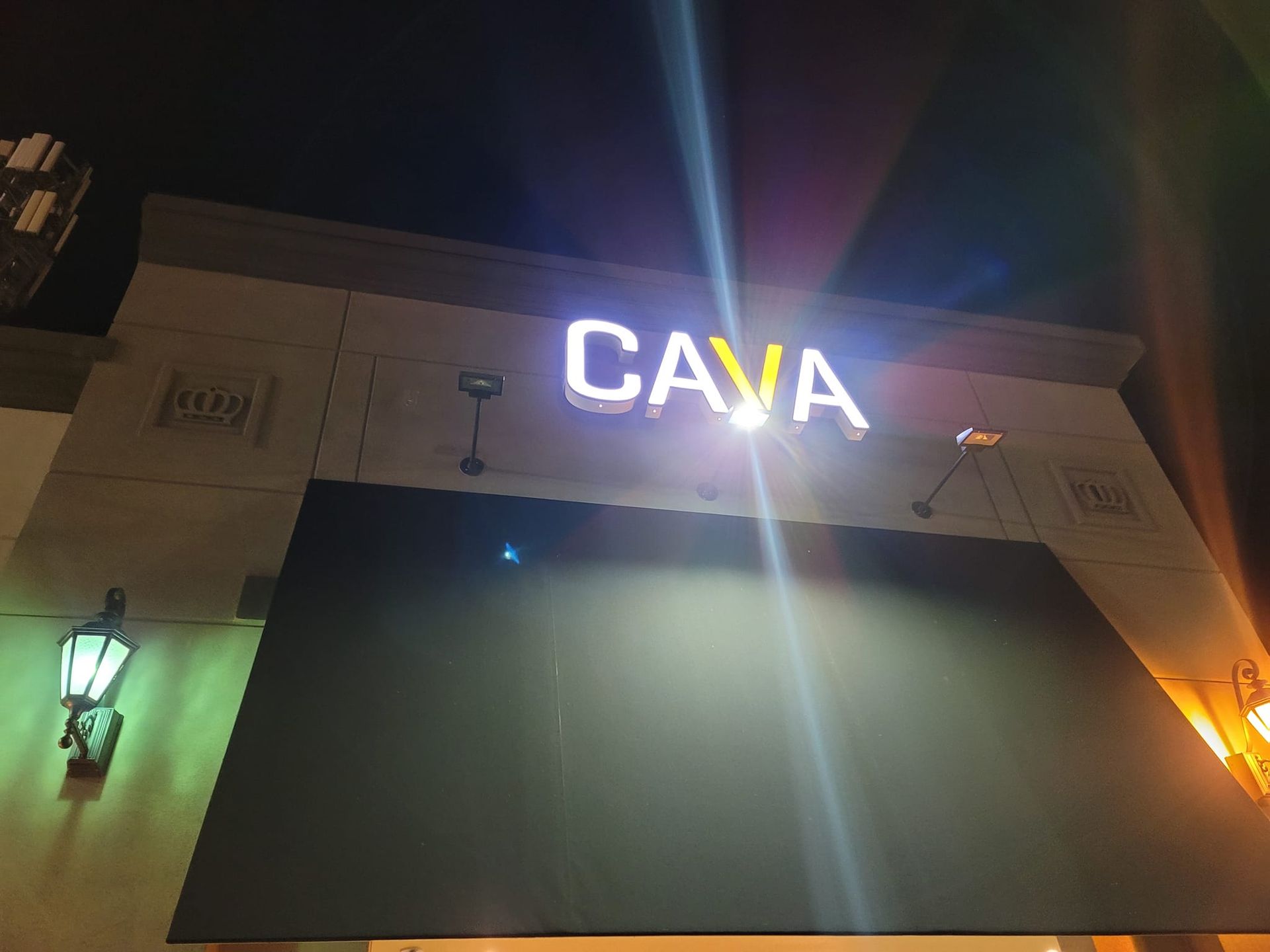 A sign for cava is lit up at night