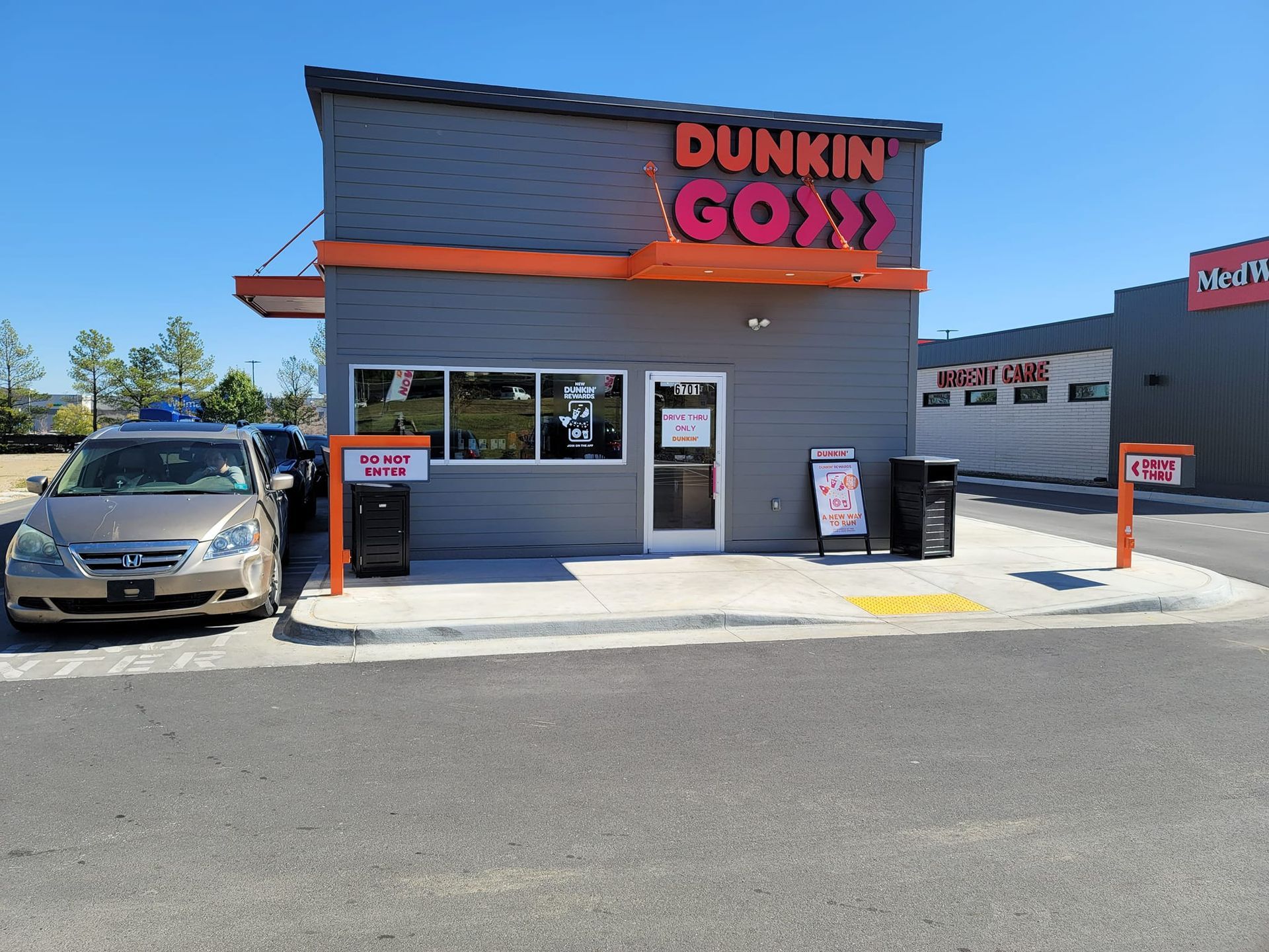 A dunkin donuts drive thru with a car parked in front of it