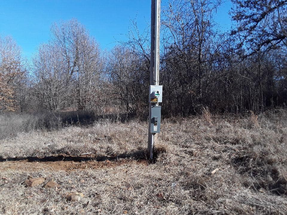A pole in the middle of a field with trees in the background.