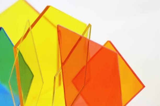 Colorful transparent plastic squares overlapping against a white background, transitioning from blue to green, yellow, and orange.