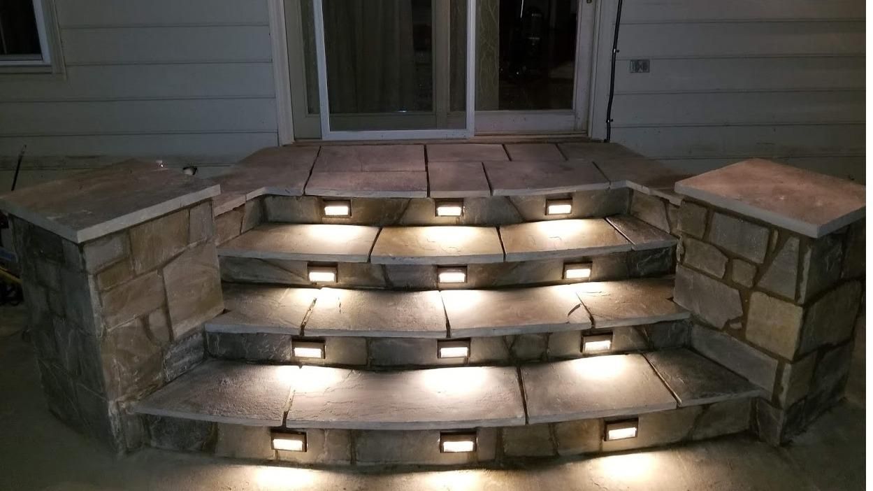 A set of stairs with lights on them in front of a house.