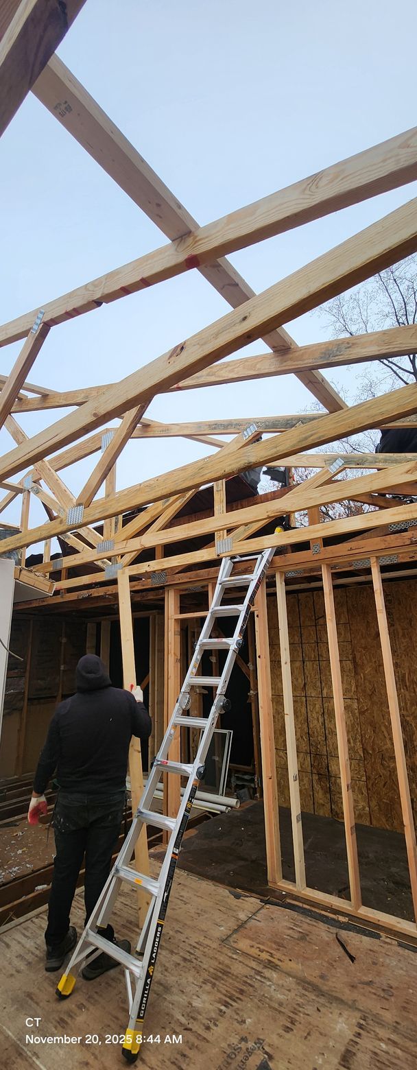 Construction worker at a building site. Wooden frame and ladder. Cloudy sky in background.