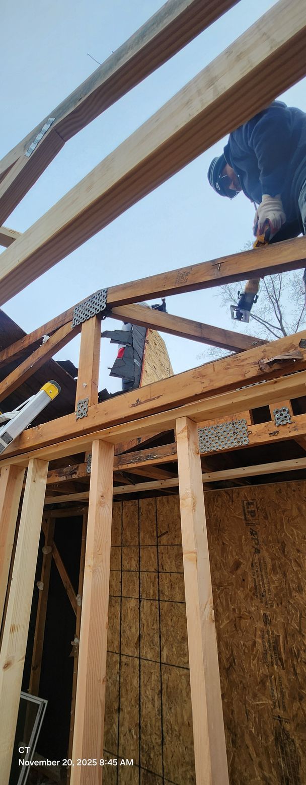 Construction workers building a wooden structure outdoors. The sky is visible.