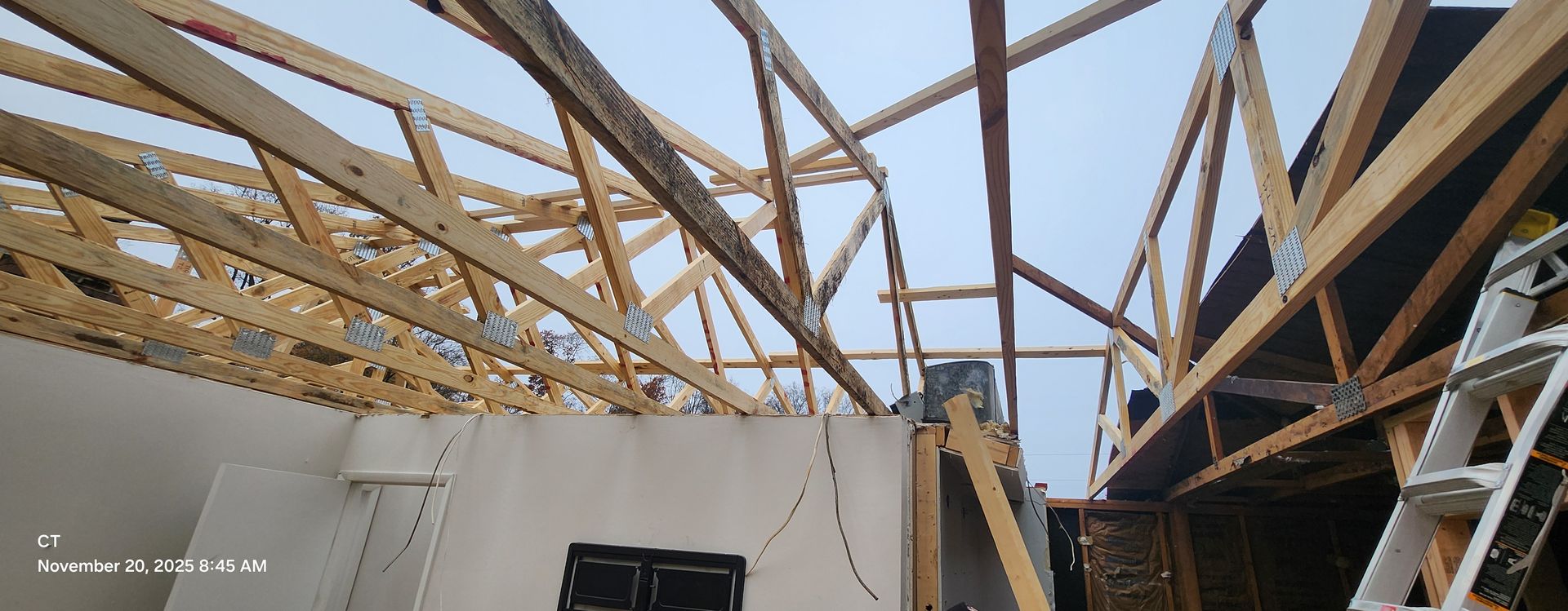 Wooden roof beams and trusses under construction. Inside a building, against a cloudy sky.
