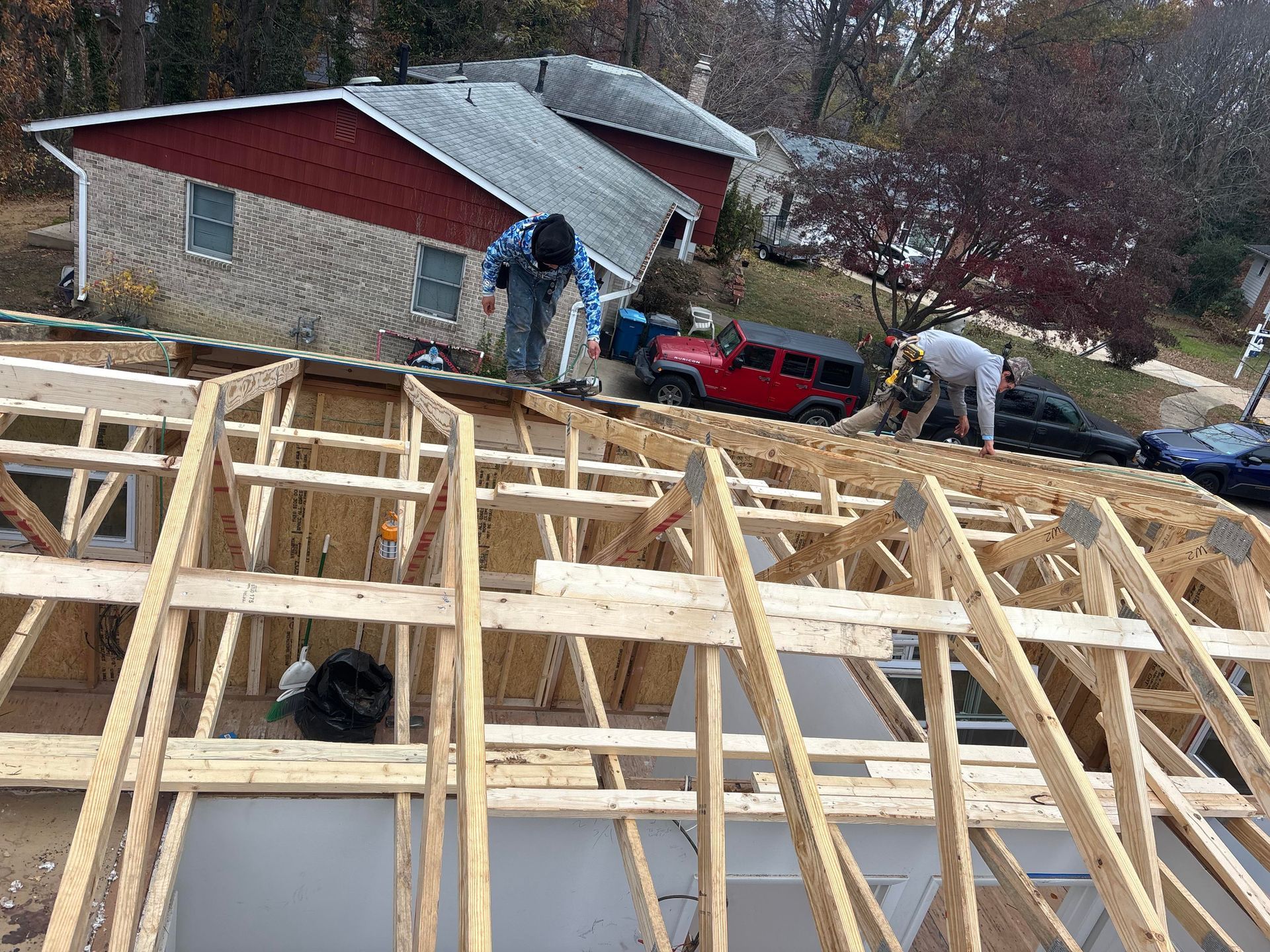 Construction workers framing a roof, suburban house in background.