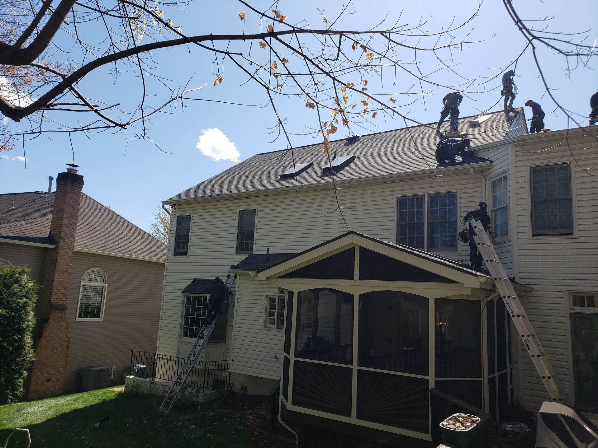 A group of people are working on the roof of a house.