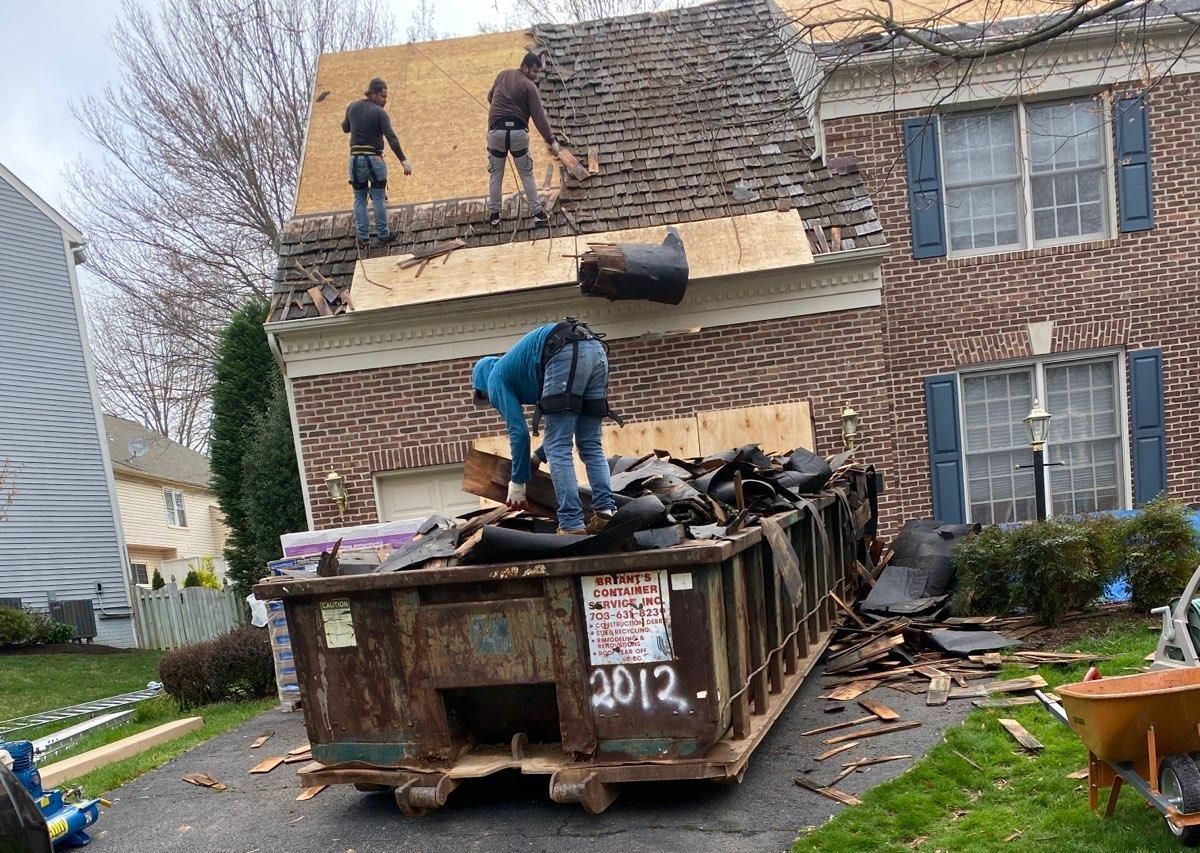 A dumpster is sitting in front of a house being demolished.