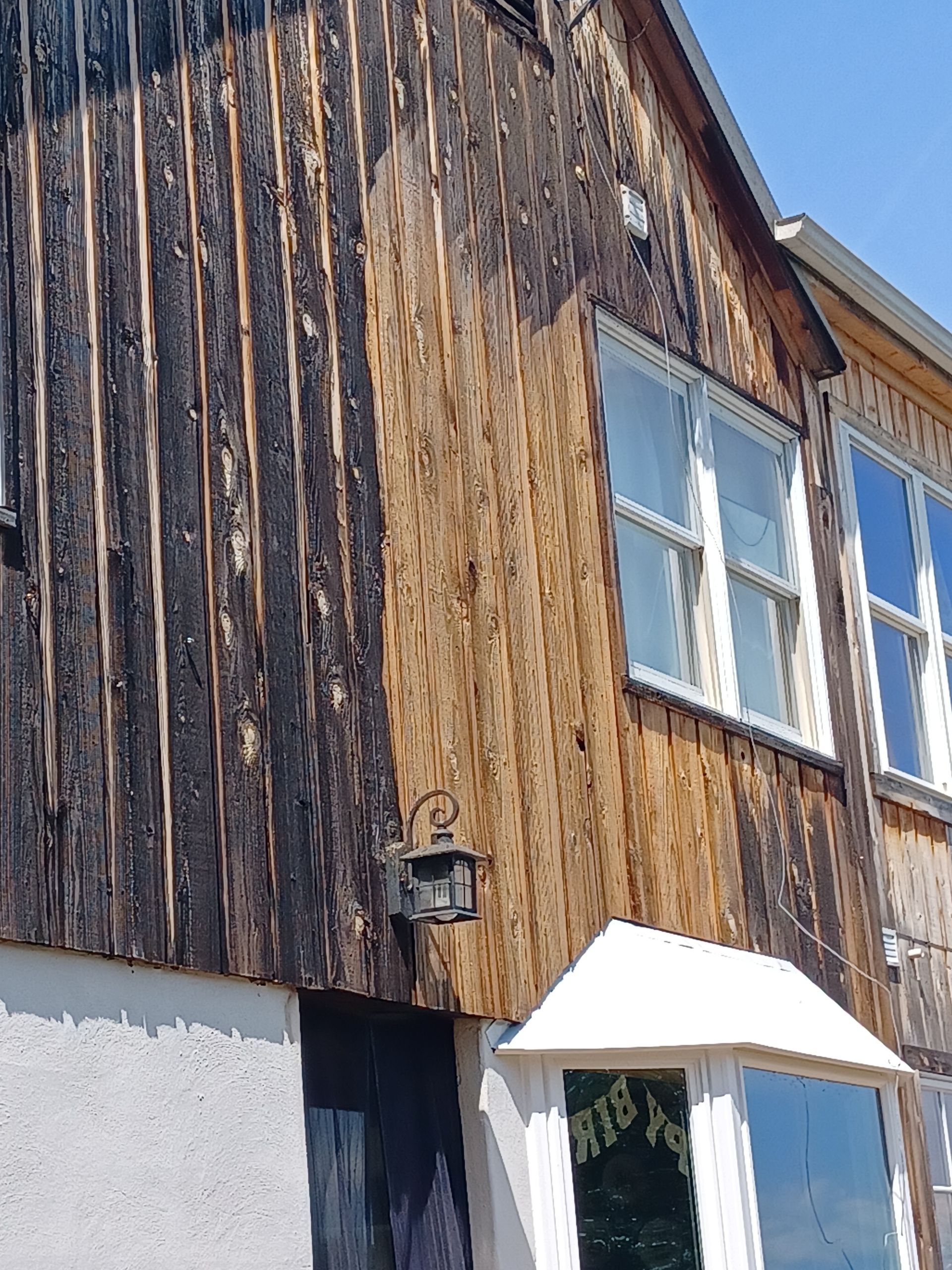 A house with a wooden siding and white windows