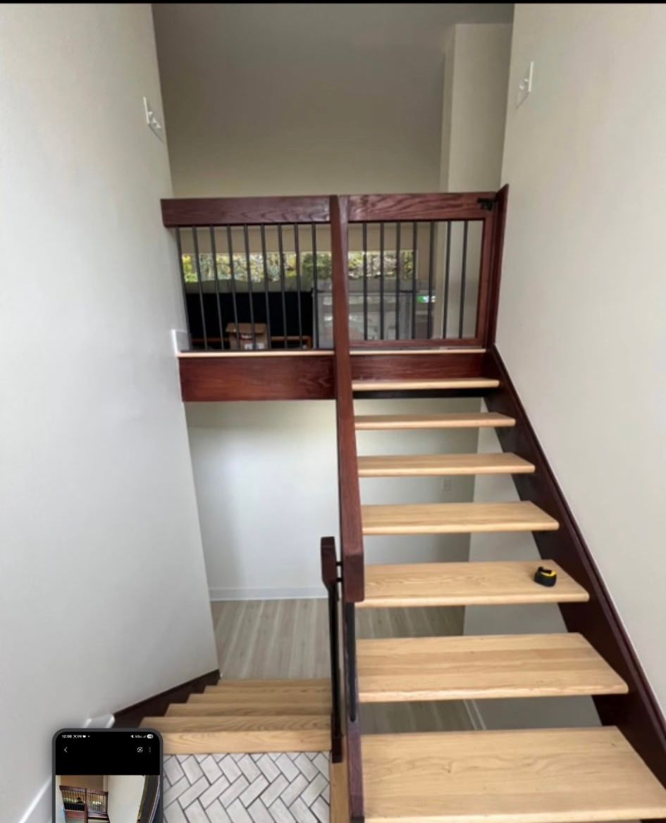 Wooden staircase with dark railing and a small landing above.
