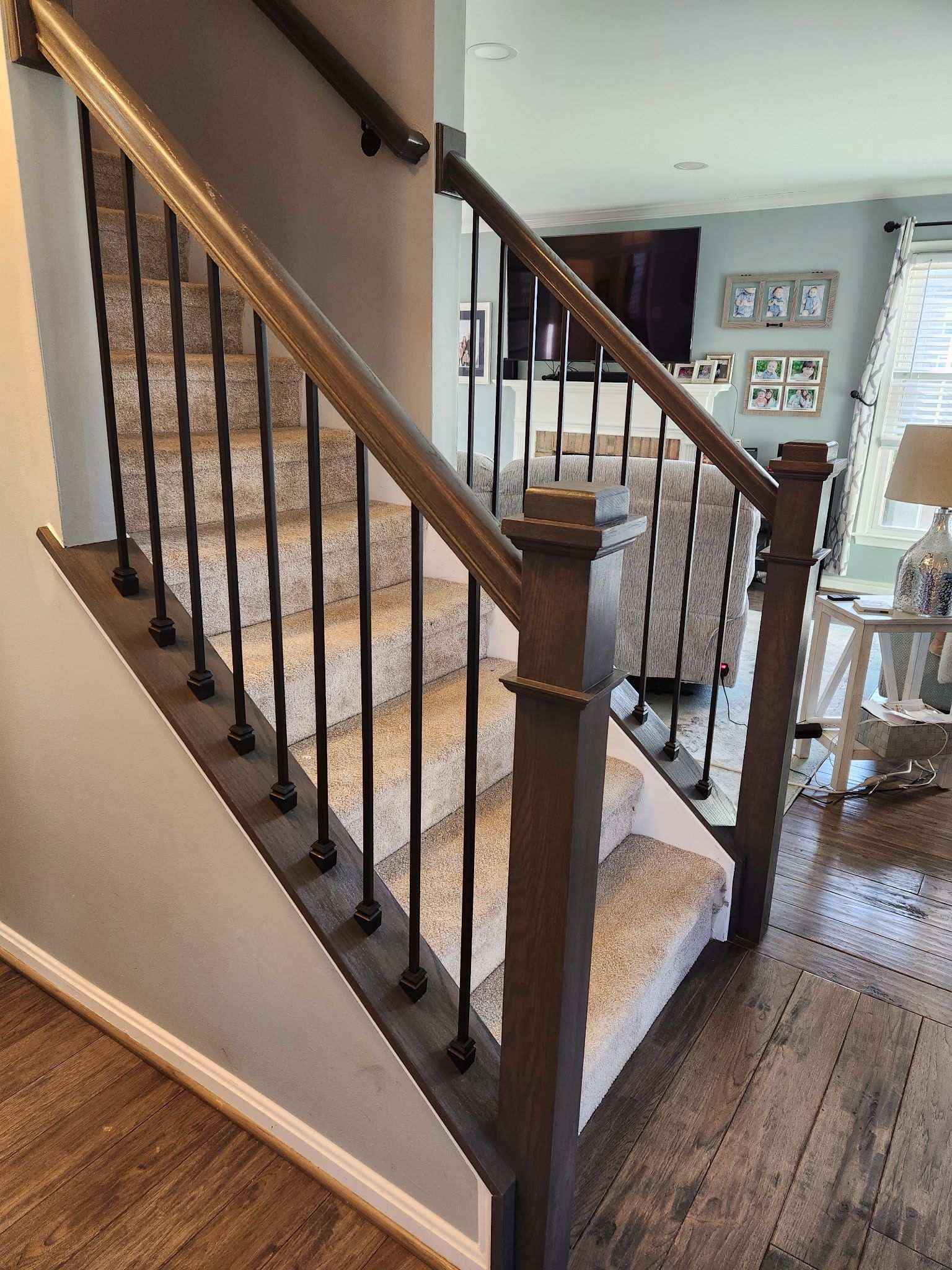 Staircase with brown wooden handrails, black metal spindles, and carpeted steps.