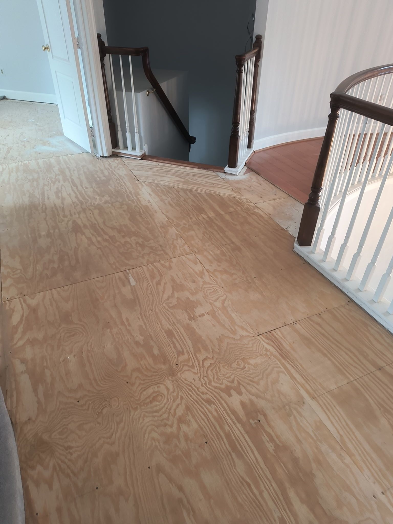 Renovated hardwood landing with staircase railings and a hallway opening ahead