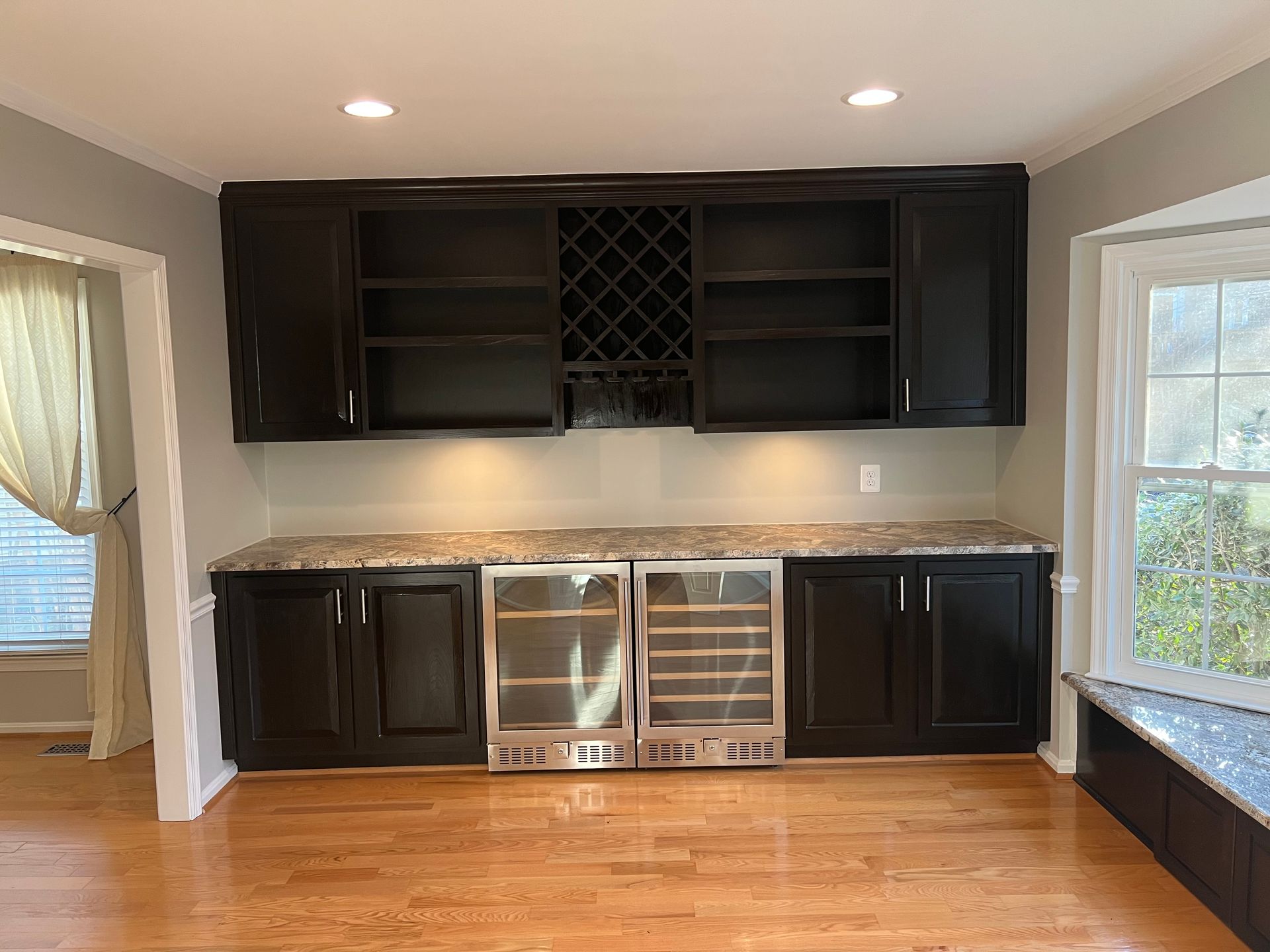 A kitchen with black cabinets , stainless steel appliances and a wine cooler.