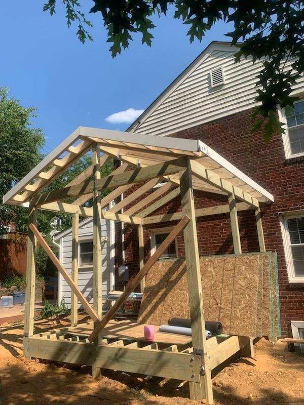 A wooden structure is being built in front of a brick house.