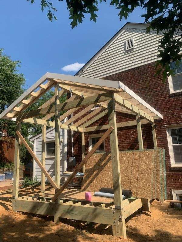 A wooden structure is being built in front of a brick house.