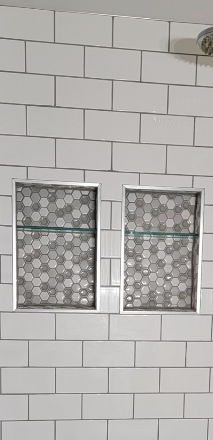 A shower stall with two shelves and a shower head.