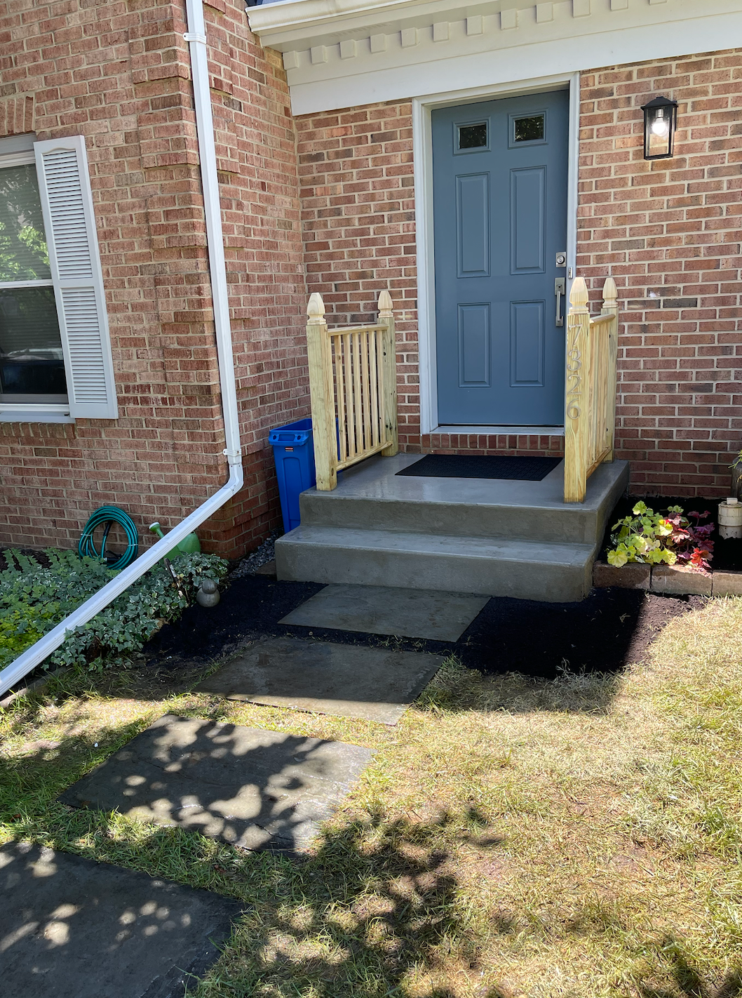 A brick house with a blue door and a concrete porch.