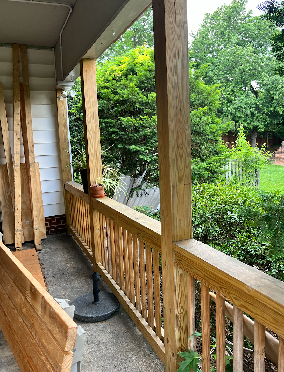 A wooden porch with a view of a garden and trees.