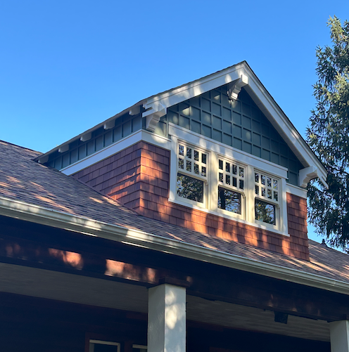A brick house with a green roof and a lot of windows
