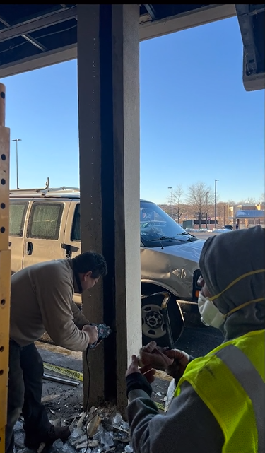 A man wearing a mask and a yellow vest is working on a building.
