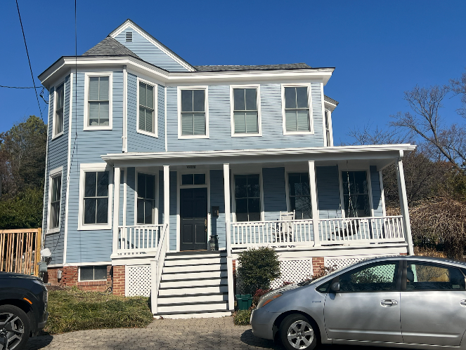 A large blue house with a car parked in front of it.