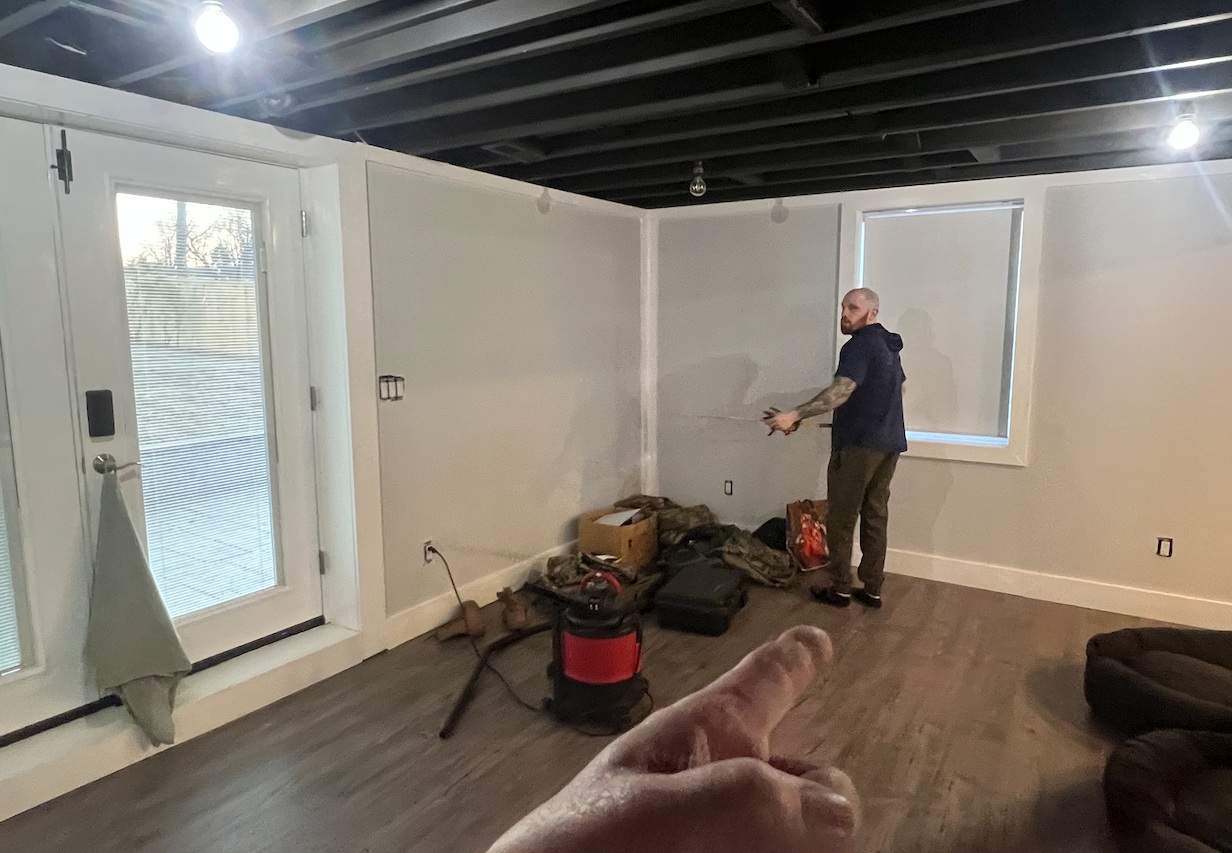 A man is standing in an empty room with a vacuum cleaner.