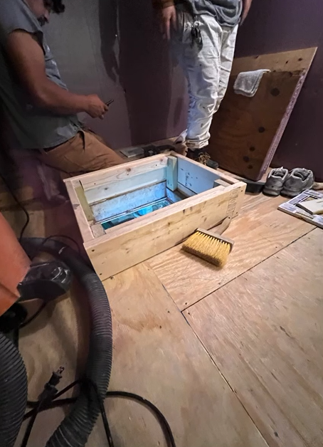 A vacuum cleaner is sitting on the floor next to a wooden box.