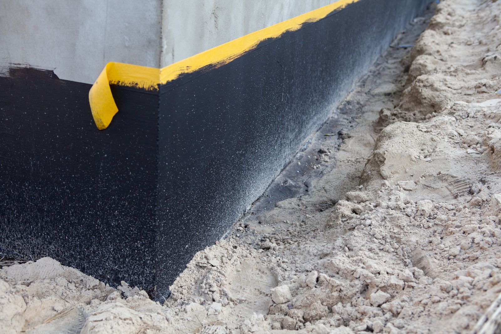 A concrete wall is being painted black and yellow
