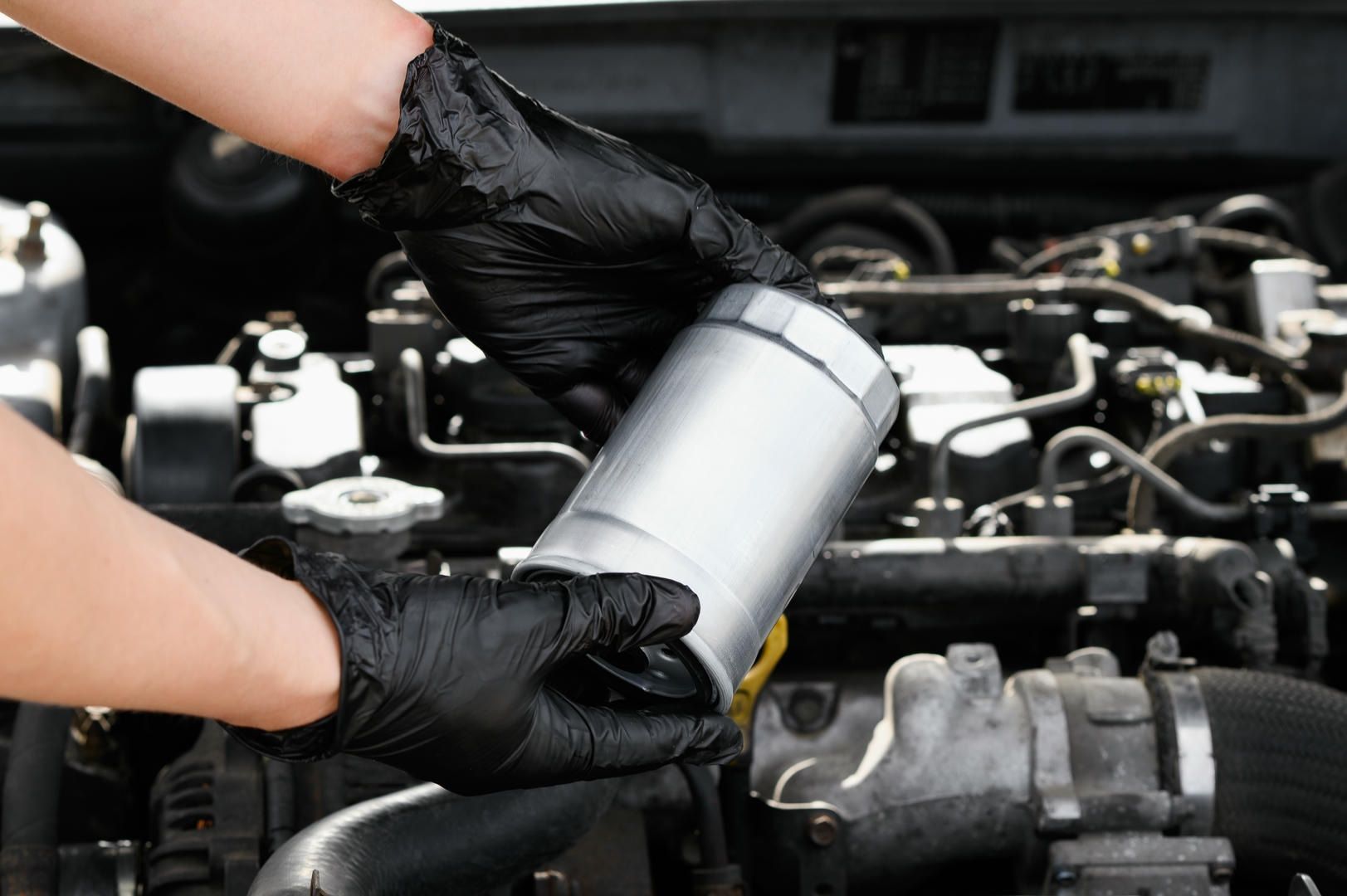 A person wearing black gloves is working on a car engine.