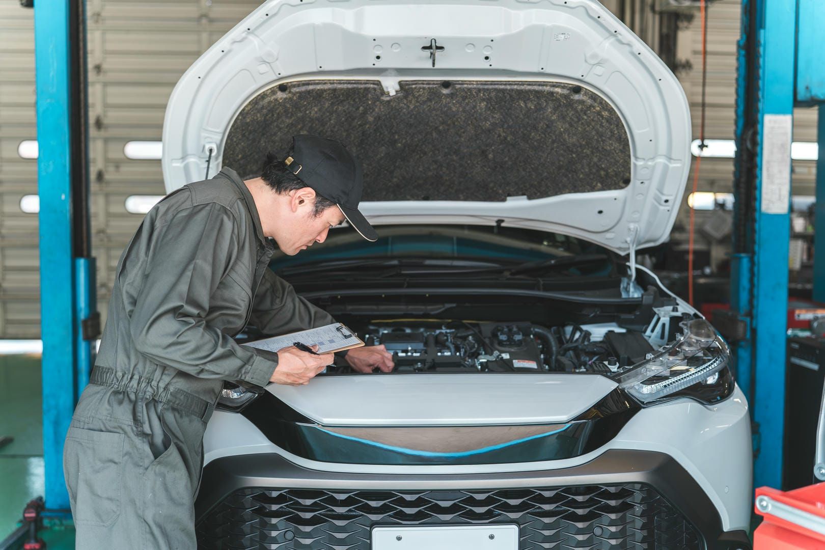 A man is working on the engine of a car in a garage.