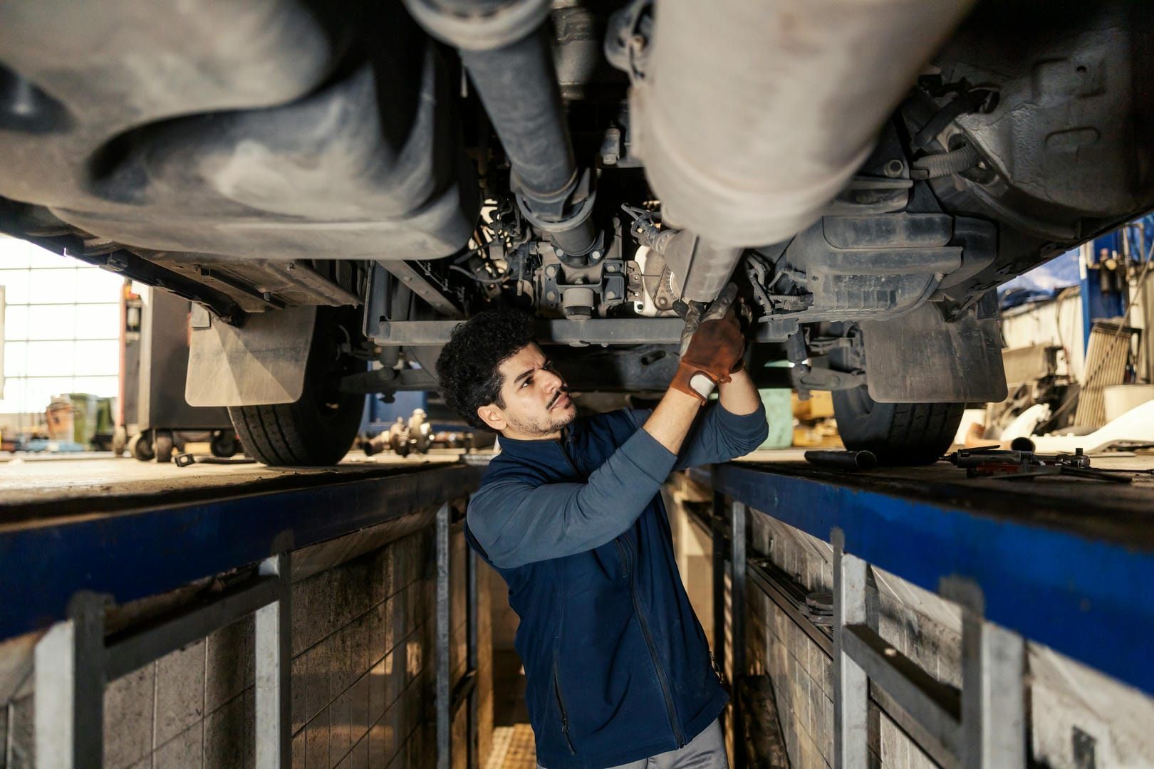 A man is working underneath a truck in a garage.