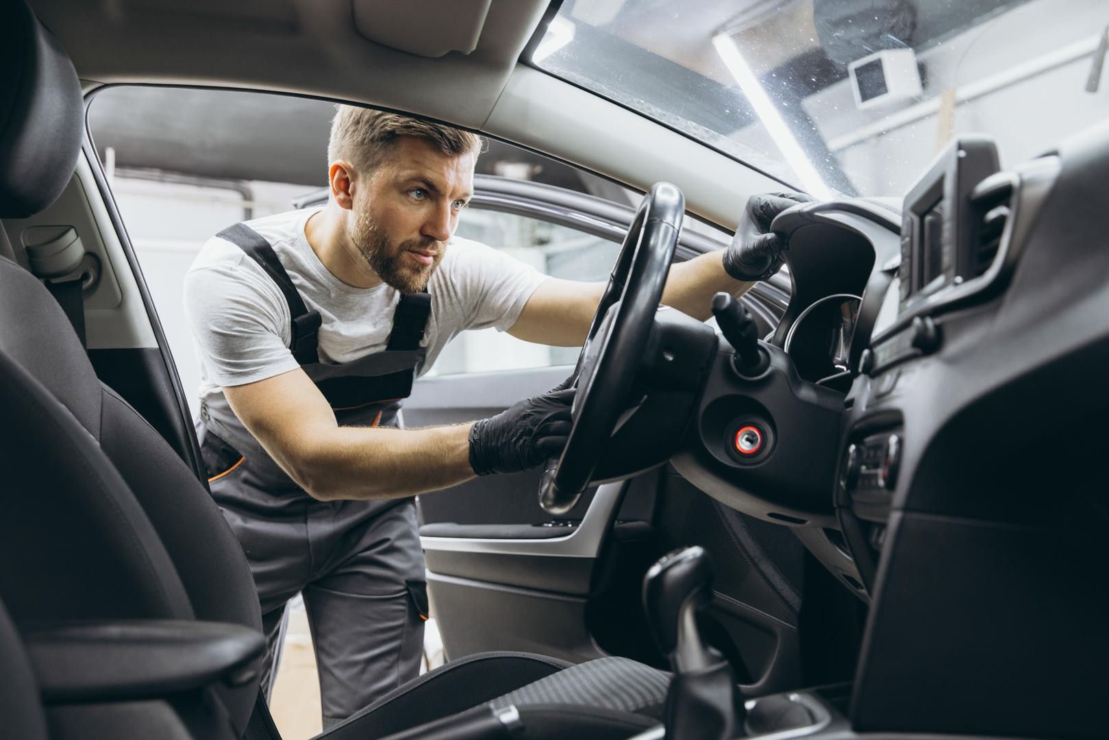 A man is cleaning the interior of a car in a garage.