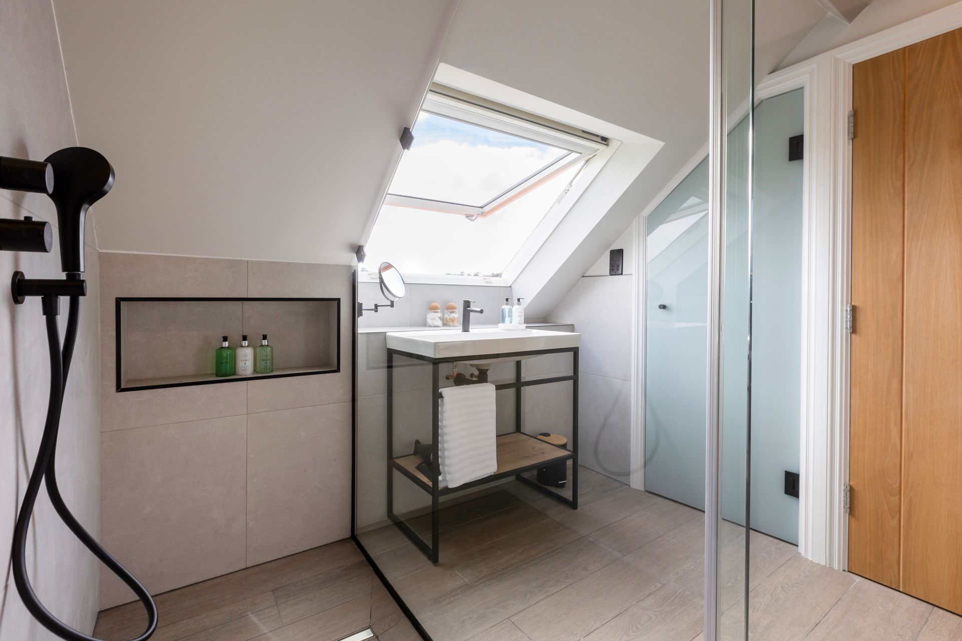A bathroom with a sink , shower , and skylight.