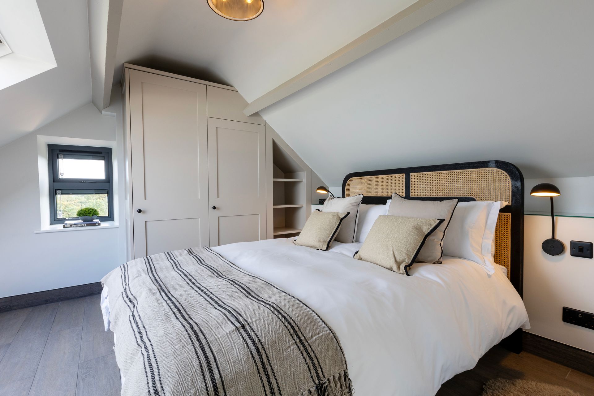 A bedroom with a king size bed and a wicker headboard.