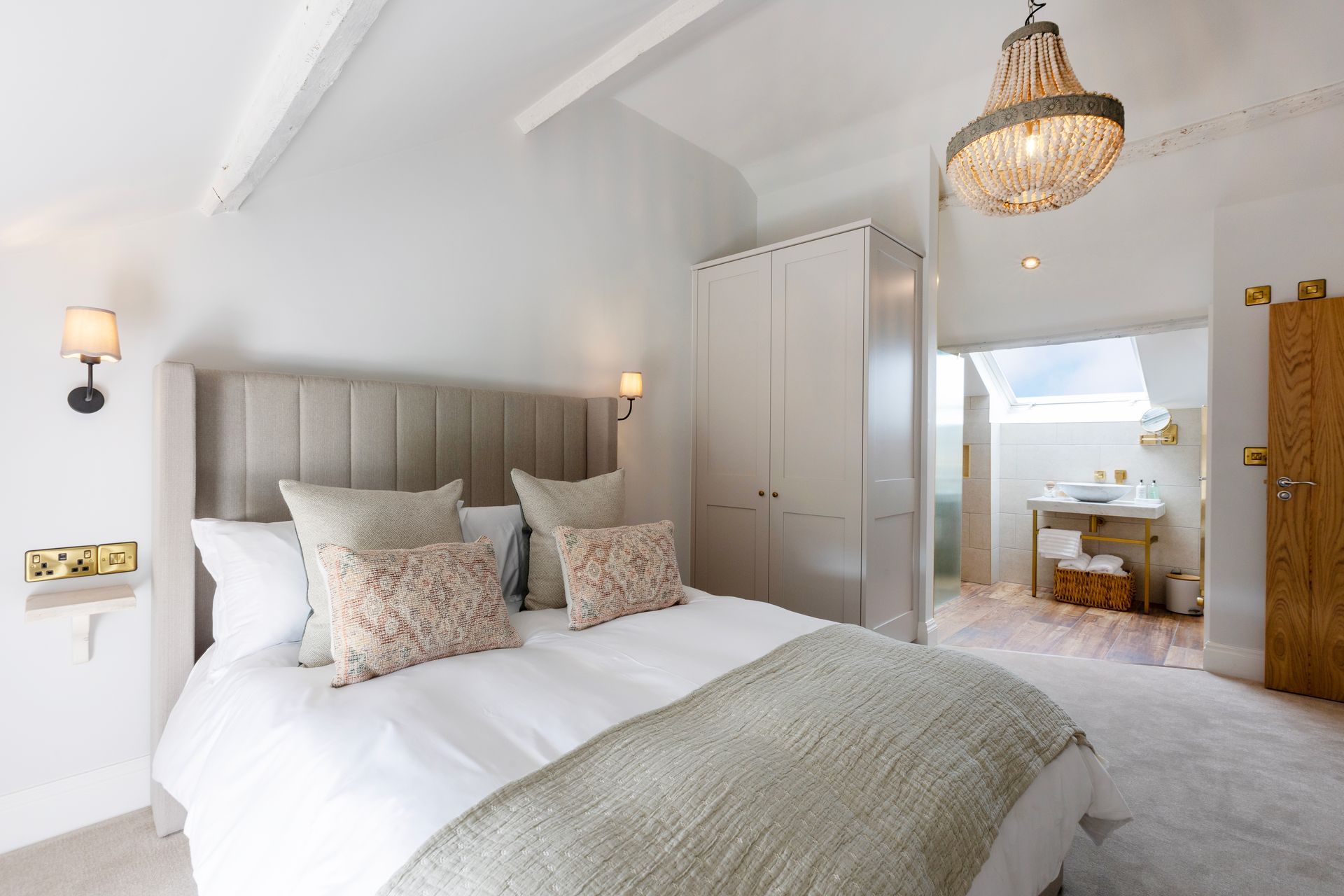 A bedroom with a large bed and a chandelier hanging from the ceiling.