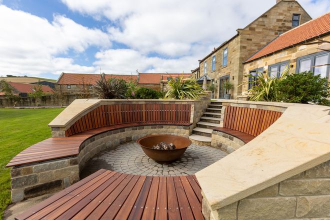 A wooden deck with a fire pit in the middle of it.