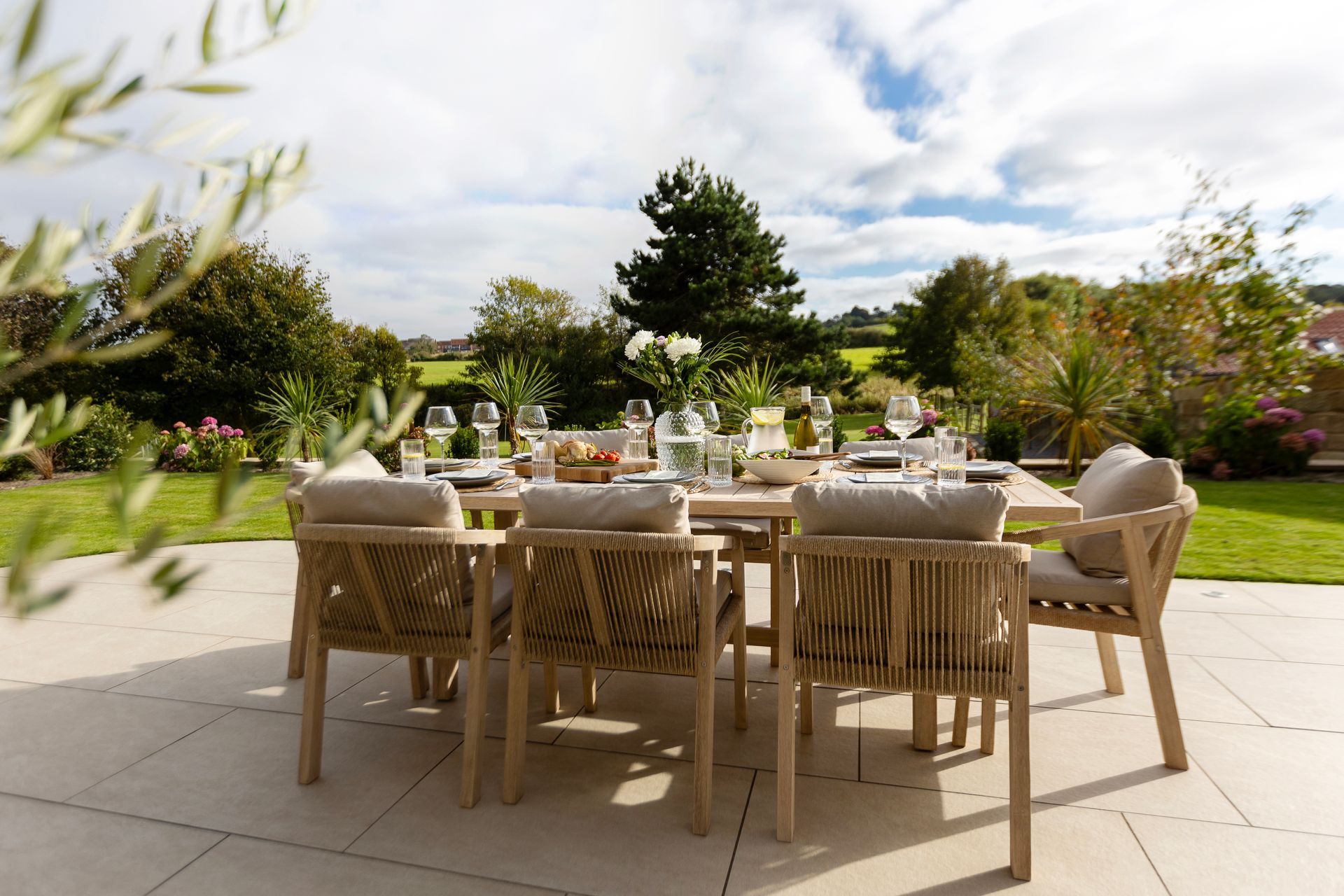 A patio with a table and chairs set up for a dinner party.
