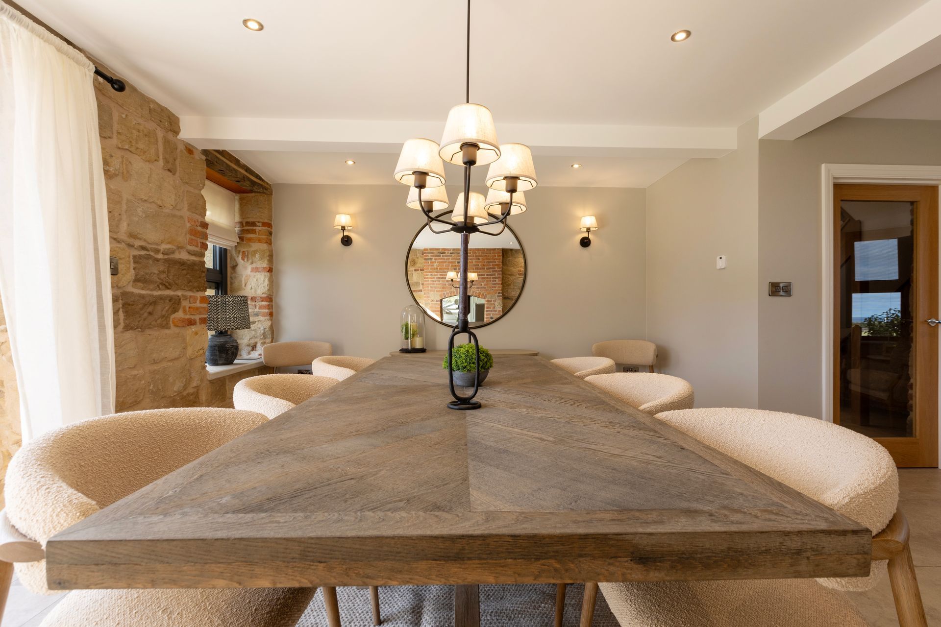 A dining room with a long wooden table and chairs and a chandelier.