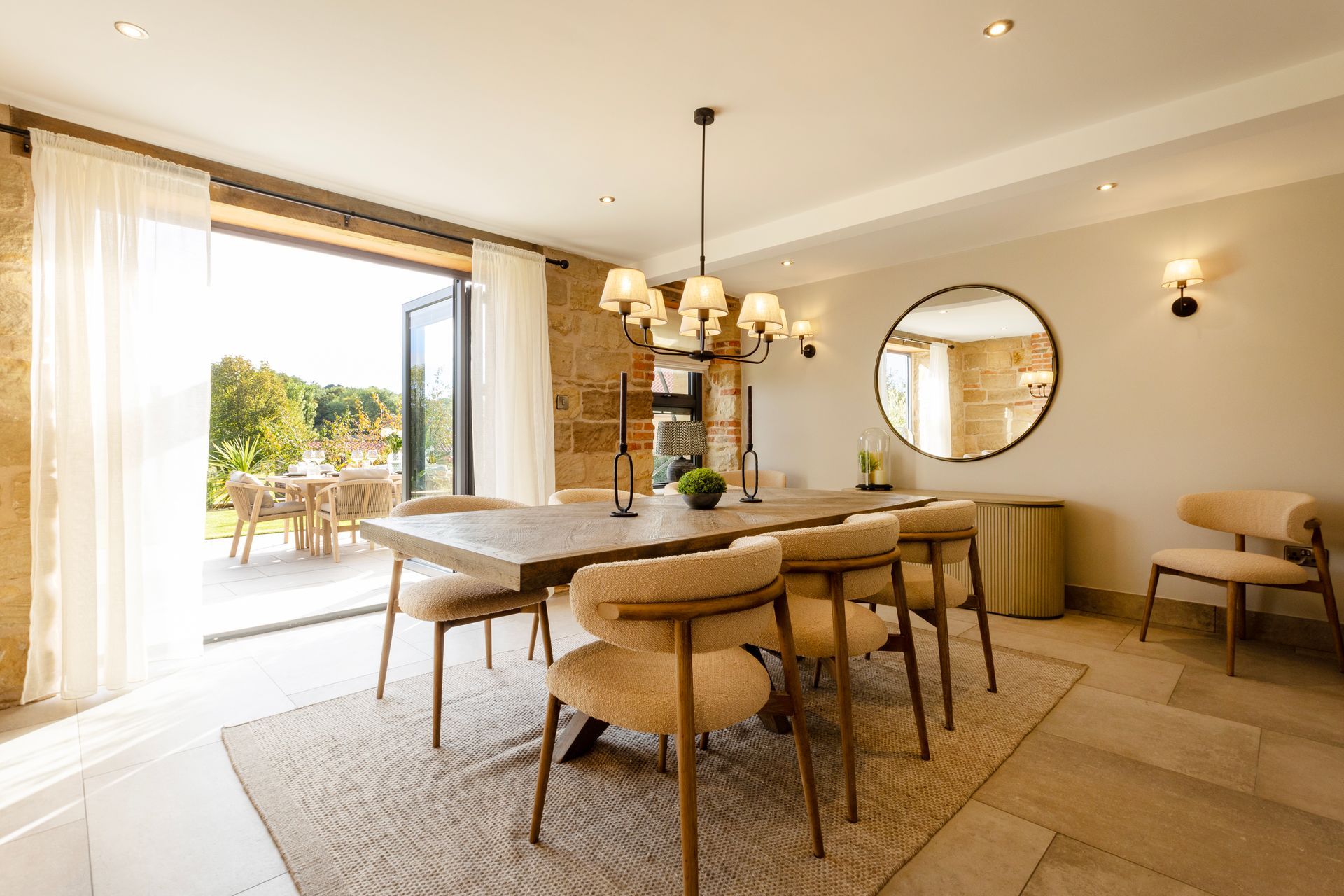 A dining room with a table and chairs and a mirror.