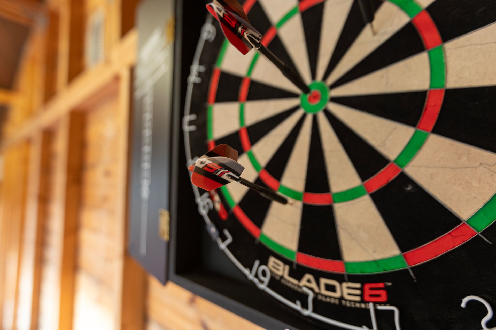 A close up of a dart board with three darts in the center.