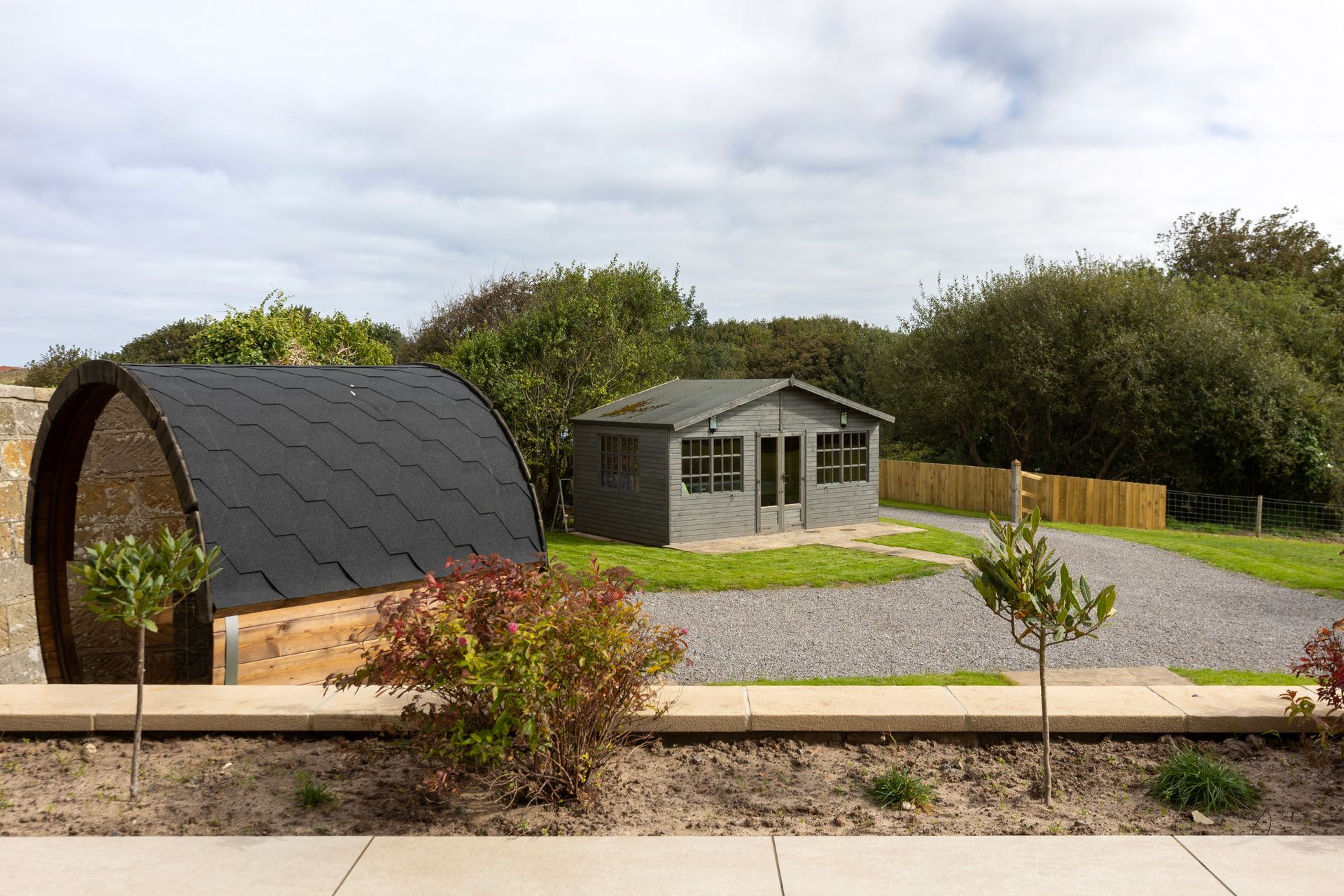 A small house is sitting in the middle of a lush green field.