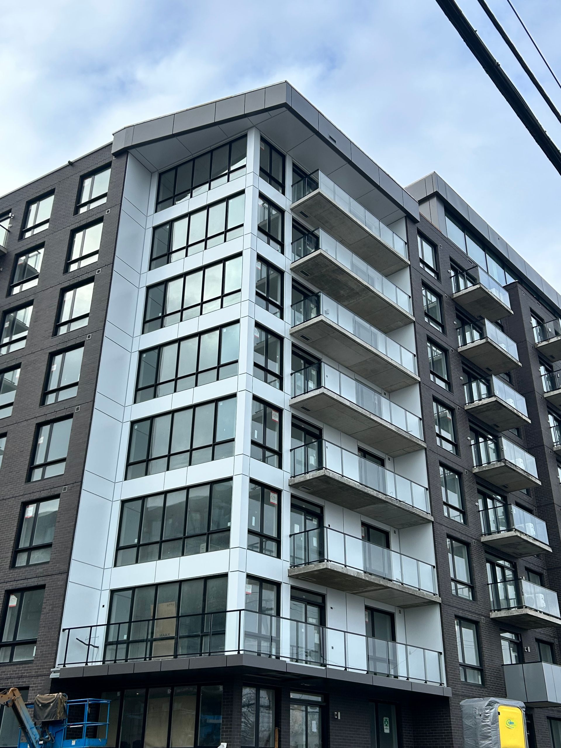 Immeuble moderne à plusieurs étages avec façade en briques, grandes fenêtres et balcons. Extérieur gris et blanc.
