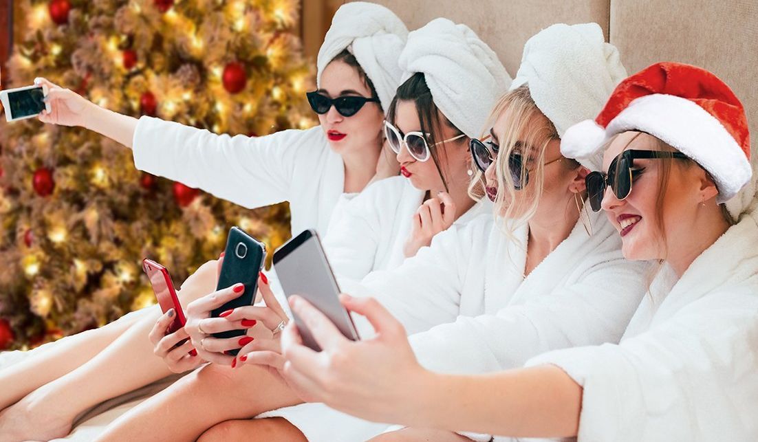 Four women in masks and robes take selfies during a spa party.