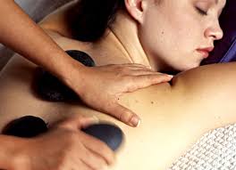 Woman receiving hot stone massage, Christmas setting, relaxed expression.