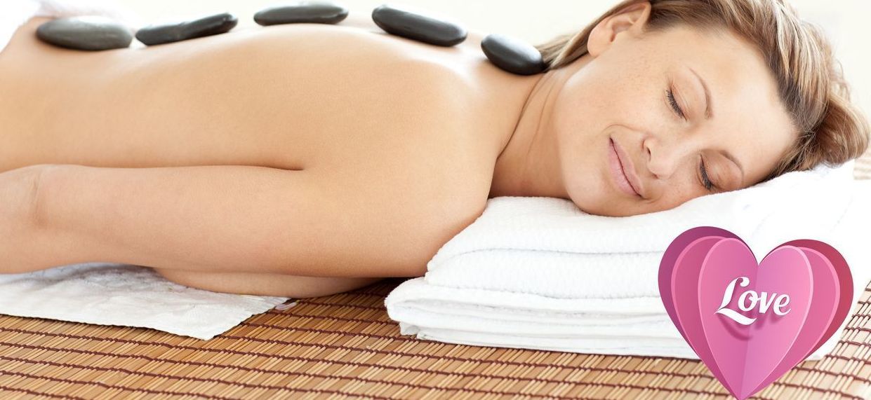 Woman receiving a shoulder massage, eyes closed, with yellow flowers on the bed.