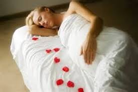 Pregnant woman sleeping on side, pink pillow, white top, red skirt.