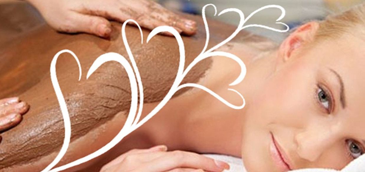 Woman receiving a back scrub treatment with cinnamon and cream on a massage table.