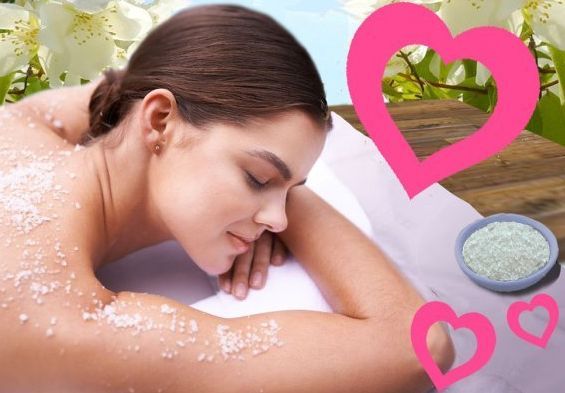 Woman receiving a massage with spa items: leaves, essential oils, cinnamon, cloves, and candle.