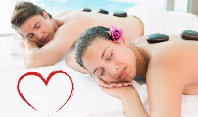 Couple receiving holiday massages at a spa. Woman and man are lying face down, receiving shoulder rubs.