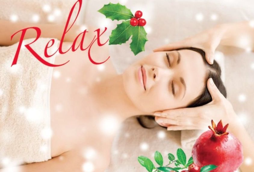 Woman receiving a massage with spa items: leaves, essential oils, cinnamon, cloves, and candle.