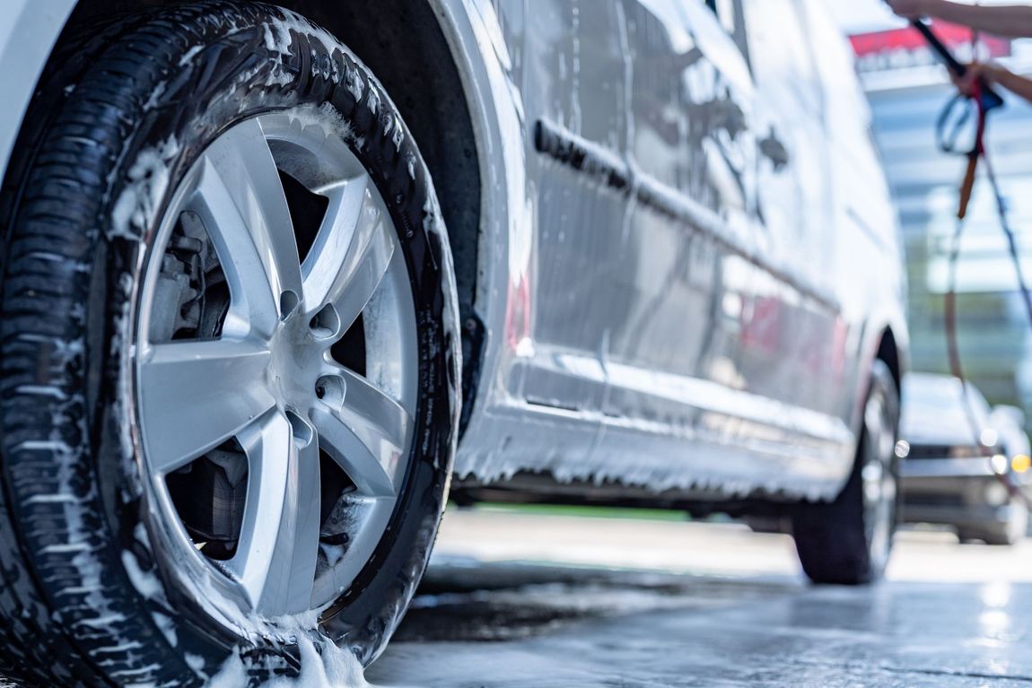 A car is being washed with soap and water at a car wash.